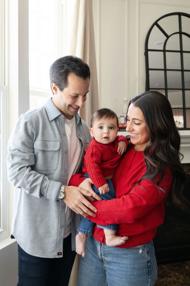 Cleveland in-home family photoshoot with mom, dad, and baby boy featuring natural light lifestyle photography, cozy candid moments, Valentine’s theme with red sweaters and chocolates, and their family dog