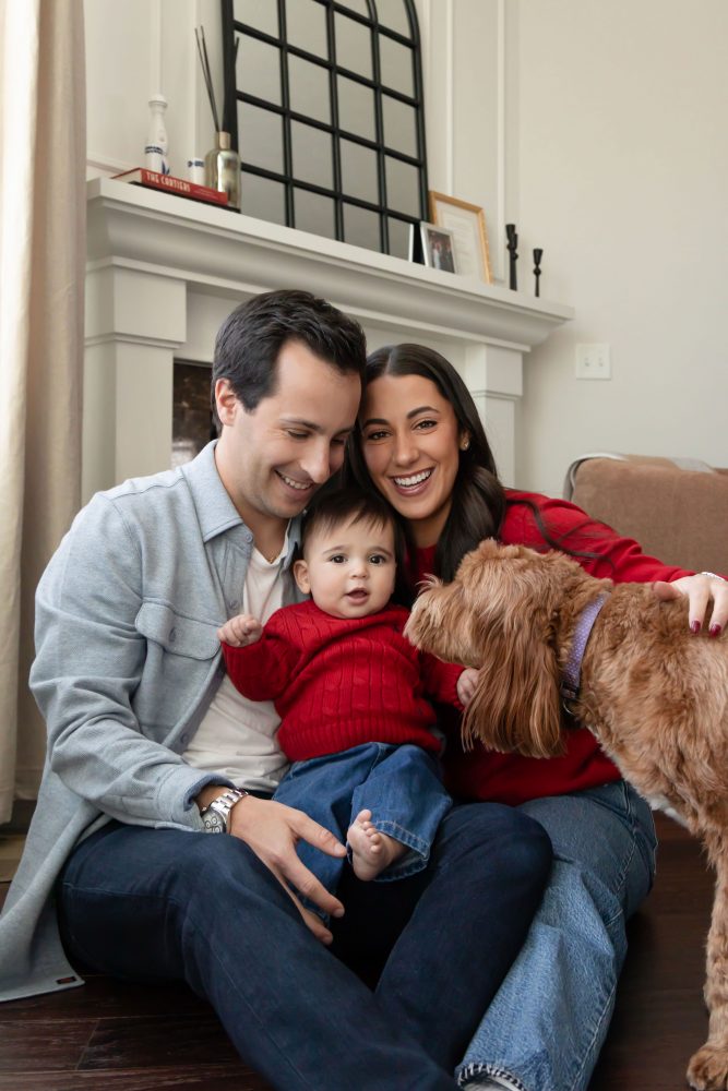 Cleveland in-home family photoshoot with mom, dad, and baby boy featuring natural light lifestyle photography, cozy candid moments, Valentine’s theme with red sweaters and chocolates, and their family dog