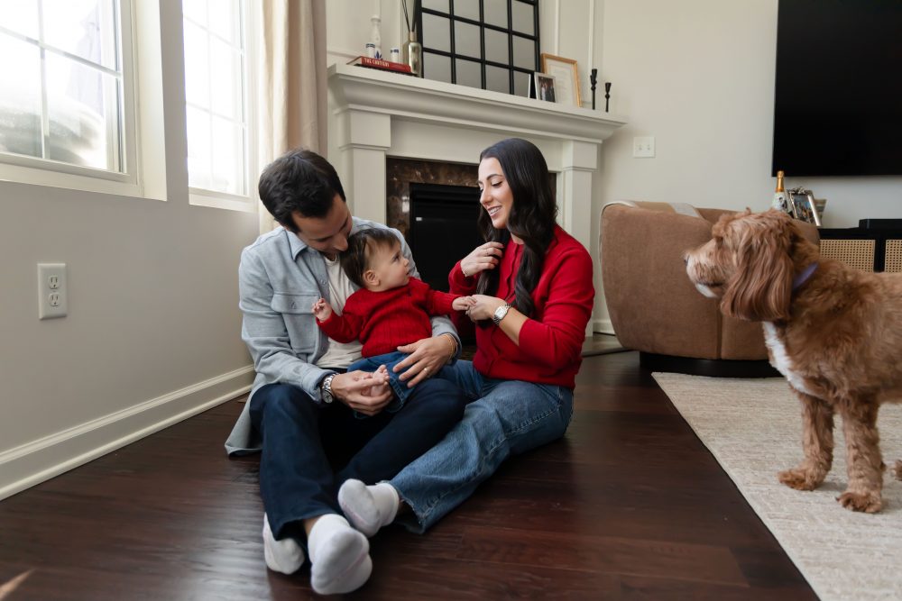 Cleveland in-home family photoshoot with mom, dad, and baby boy featuring natural light lifestyle photography, cozy candid moments, Valentine’s theme with red sweaters and chocolates, and their family dog