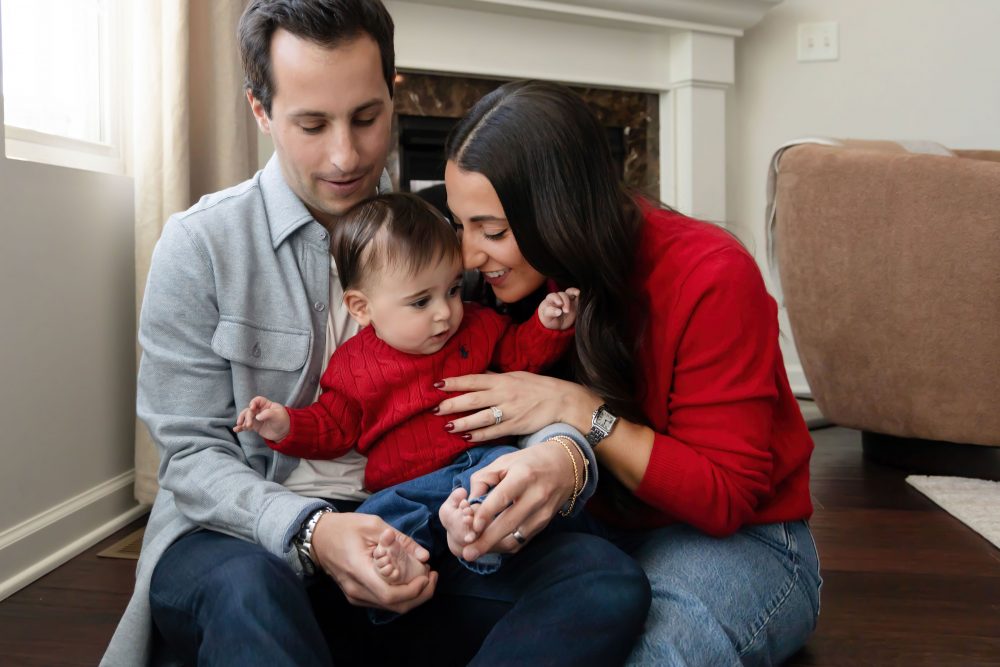 Cleveland in-home family photoshoot with mom, dad, and baby boy featuring natural light lifestyle photography, cozy candid moments, Valentine’s theme with red sweaters and chocolates, and their family dog