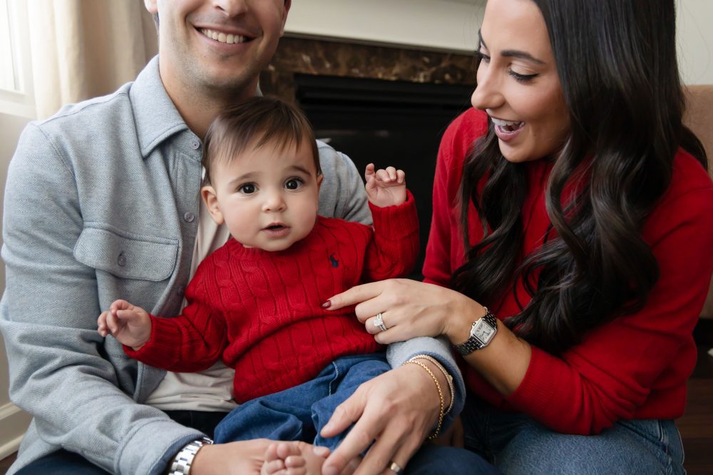 Cleveland in-home family photoshoot with mom, dad, and baby boy featuring natural light lifestyle photography, cozy candid moments, Valentine’s theme with red sweaters and chocolates, and their family dog
