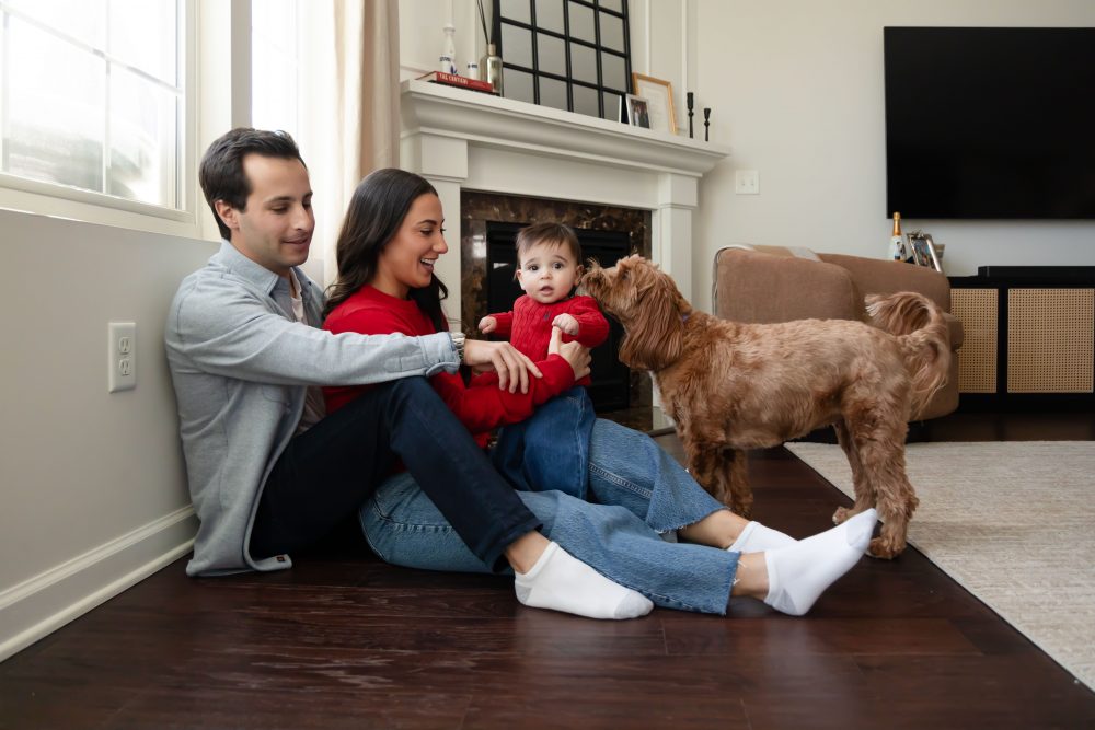Cleveland in-home family photoshoot with mom, dad, and baby boy featuring natural light lifestyle photography, cozy candid moments, Valentine’s theme with red sweaters and chocolates, and their family dog