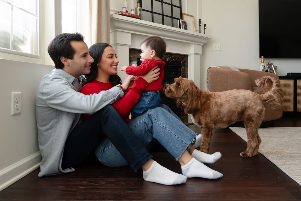 Cleveland in-home family photoshoot with mom, dad, and baby boy featuring natural light lifestyle photography, cozy candid moments, Valentine’s theme with red sweaters and chocolates, and their family dog