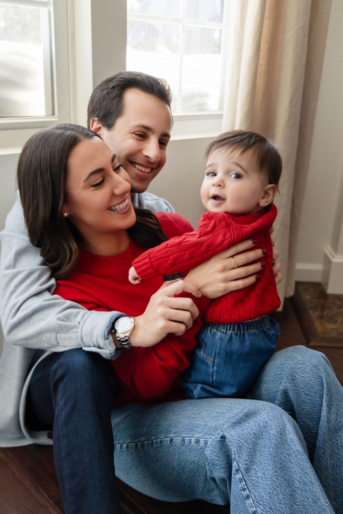 Cleveland in-home family photoshoot with mom, dad, and baby boy featuring natural light lifestyle photography, cozy candid moments, Valentine’s theme with red sweaters and chocolates, and their family dog