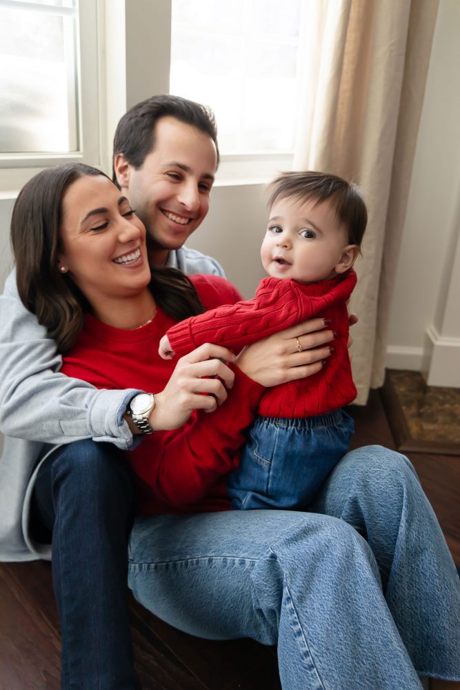 Cleveland in-home family photoshoot with mom, dad, and baby boy featuring natural light lifestyle photography, cozy candid moments, Valentine’s theme with red sweaters and chocolates, and their family dog