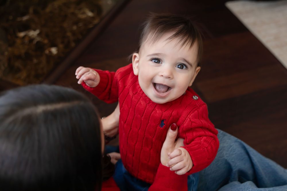 Cleveland in-home family photoshoot with mom, dad, and baby boy featuring natural light lifestyle photography, cozy candid moments, Valentine’s theme with red sweaters and chocolates, and their family dog