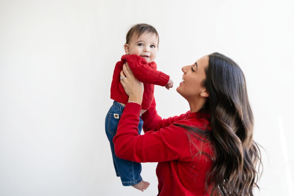 Cleveland in-home family photoshoot with mom, dad, and baby boy featuring natural light lifestyle photography, cozy candid moments, Valentine’s theme with red sweaters and chocolates, and their family dog