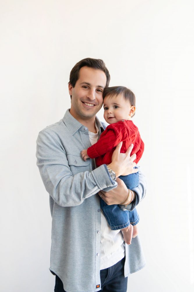 Cleveland in-home family photoshoot with mom, dad, and baby boy featuring natural light lifestyle photography, cozy candid moments, Valentine’s theme with red sweaters and chocolates, and their family dog