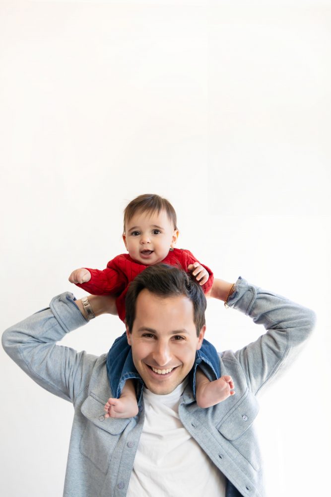 Cleveland in-home family photoshoot with mom, dad, and baby boy featuring natural light lifestyle photography, cozy candid moments, Valentine’s theme with red sweaters and chocolates, and their family dog