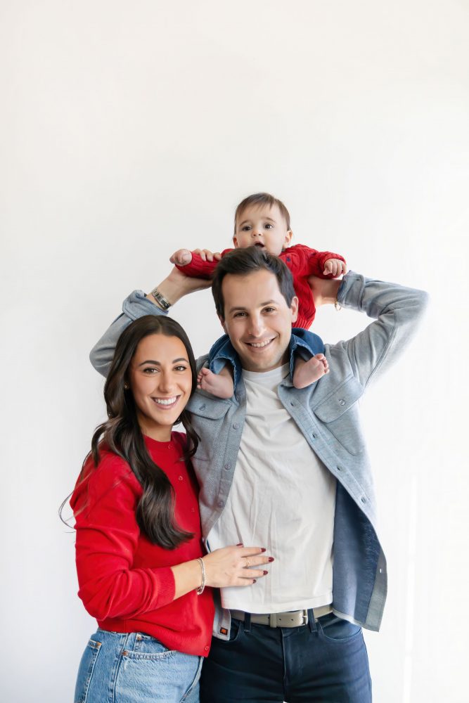 Cleveland in-home family photoshoot with mom, dad, and baby boy featuring natural light lifestyle photography, cozy candid moments, Valentine’s theme with red sweaters and chocolates, and their family dog