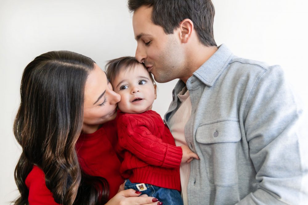 Cleveland in-home family photoshoot with mom, dad, and baby boy featuring natural light lifestyle photography, cozy candid moments, Valentine’s theme with red sweaters and chocolates, and their family dog