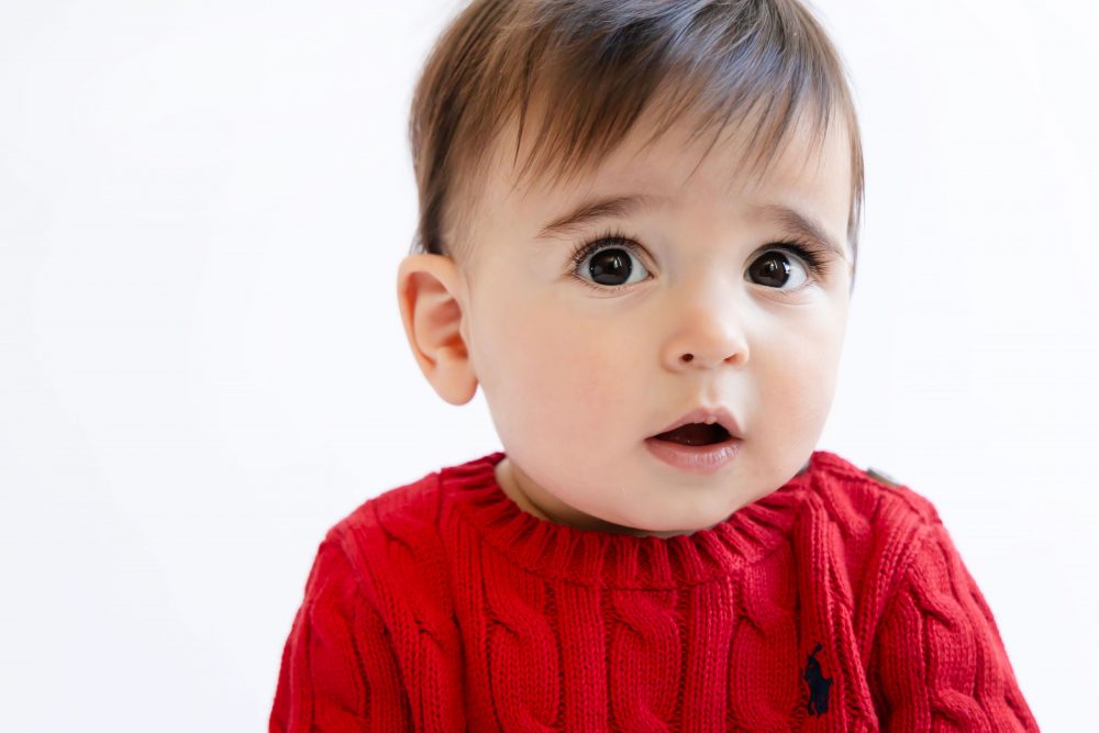 Cleveland in-home family photoshoot with mom, dad, and baby boy featuring natural light lifestyle photography, cozy candid moments, Valentine’s theme with red sweaters and chocolates, and their family dog