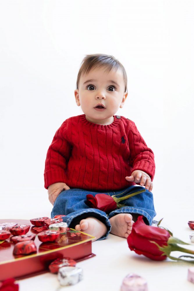 Cleveland in-home family photoshoot with mom, dad, and baby boy featuring natural light lifestyle photography, cozy candid moments, Valentine’s theme with red sweaters and chocolates, and their family dog