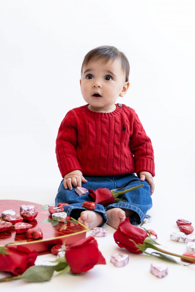 Cleveland in-home family photoshoot with mom, dad, and baby boy featuring natural light lifestyle photography, cozy candid moments, Valentine’s theme with red sweaters and chocolates, and their family dog