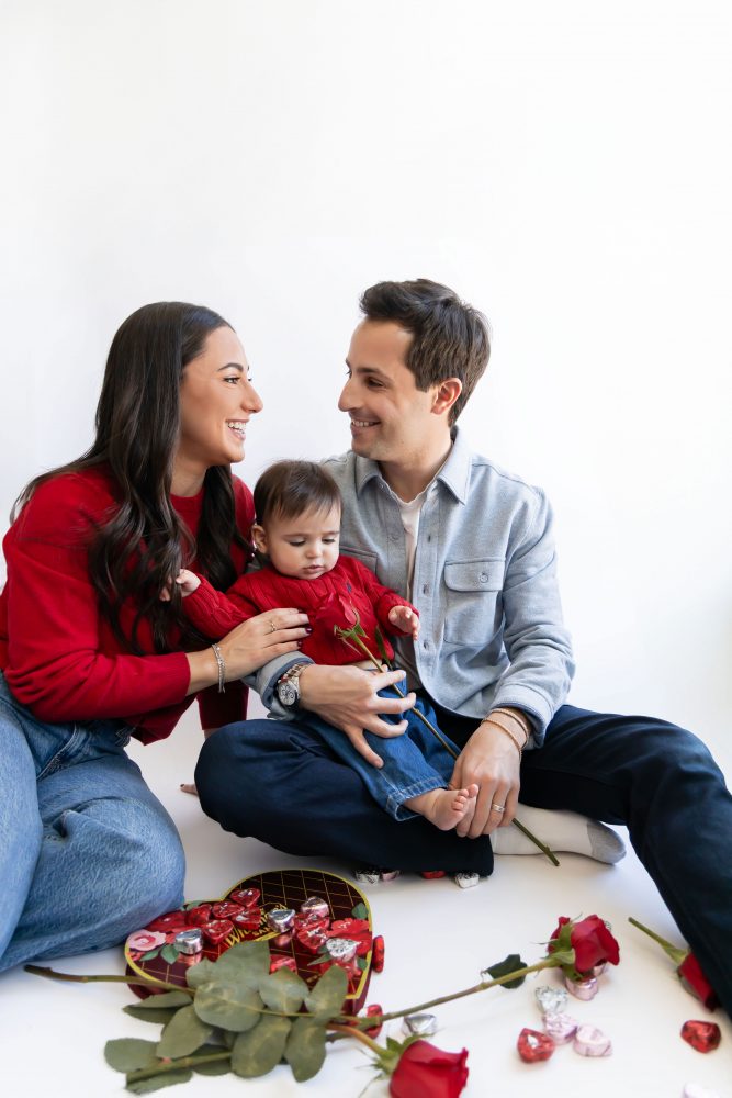 Cleveland in-home family photoshoot with mom, dad, and baby boy featuring natural light lifestyle photography, cozy candid moments, Valentine’s theme with red sweaters and chocolates, and their family dog