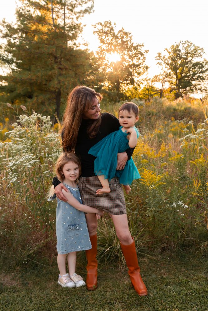 Mother with two young daughters hugging during outdoor sunset photography session in Cleveland Ohio