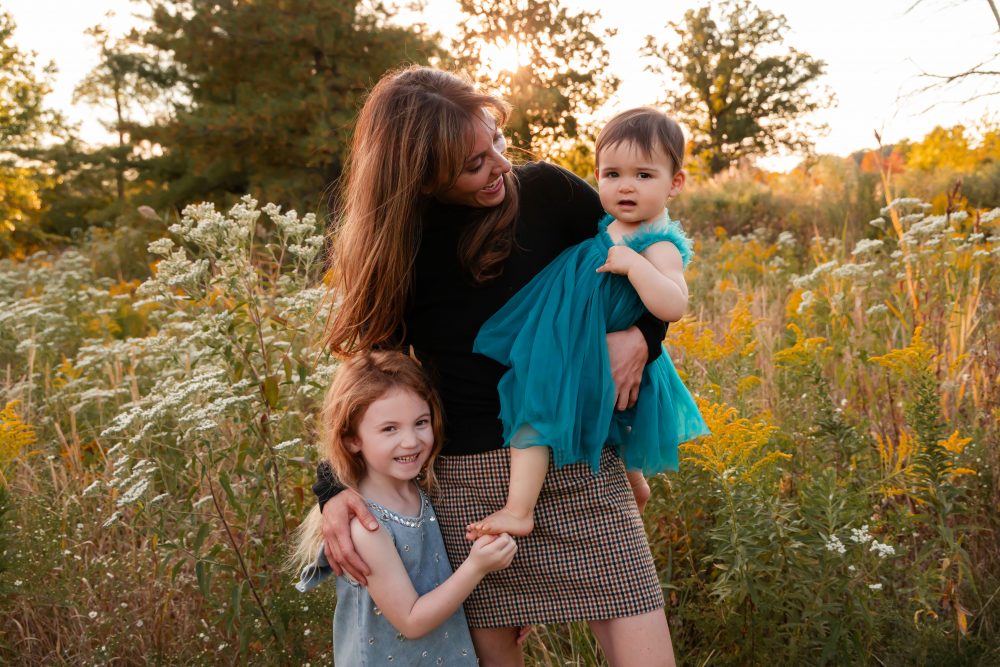 Mother with two young daughters hugging during outdoor sunset photography session in Cleveland Ohio