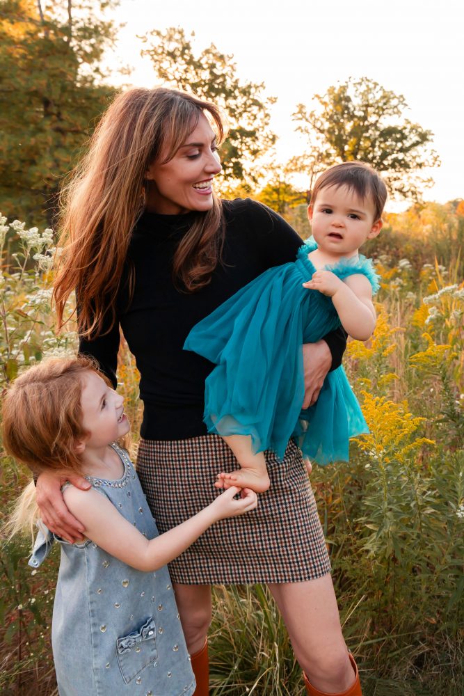 Mother with two young daughters hugging during outdoor sunset photography session in Cleveland Ohio