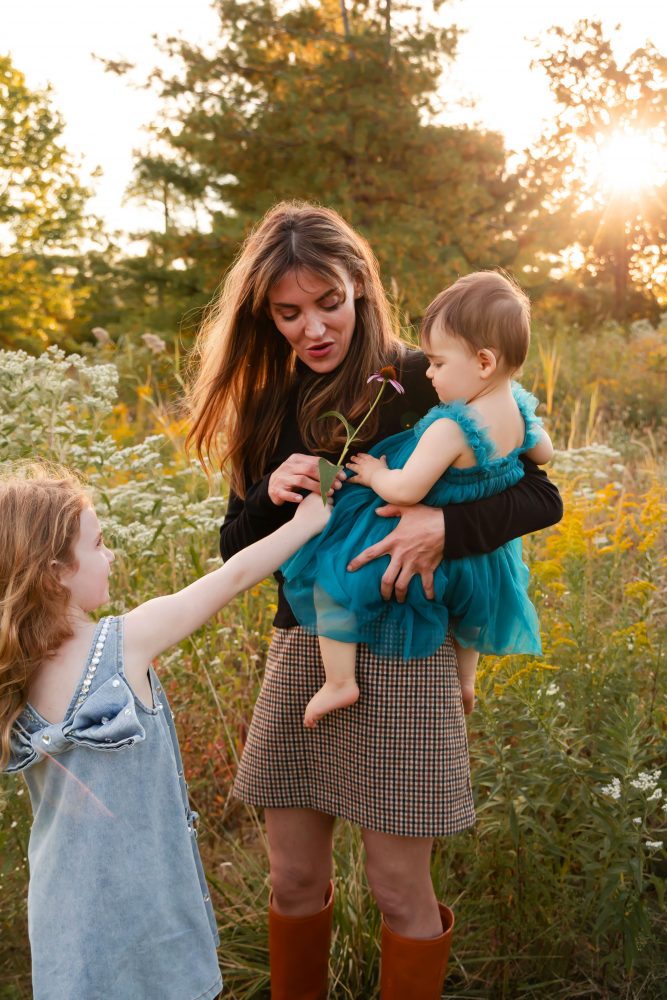 Mother with two young daughters hugging during outdoor sunset photography session in Cleveland Ohio
