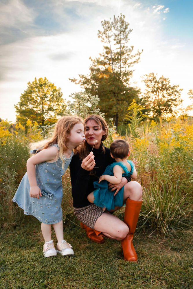 Mother with two young daughters hugging during outdoor sunset photography session in Cleveland Ohio