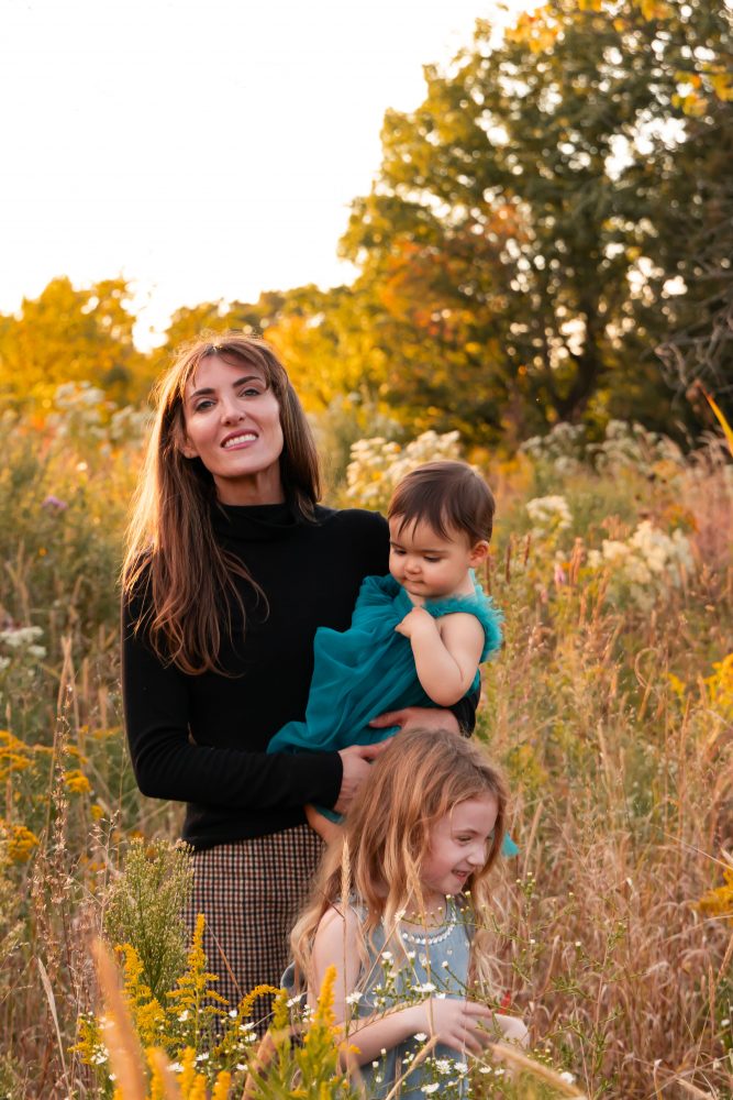 Mother with two young daughters hugging during outdoor sunset photography session in Cleveland Ohio