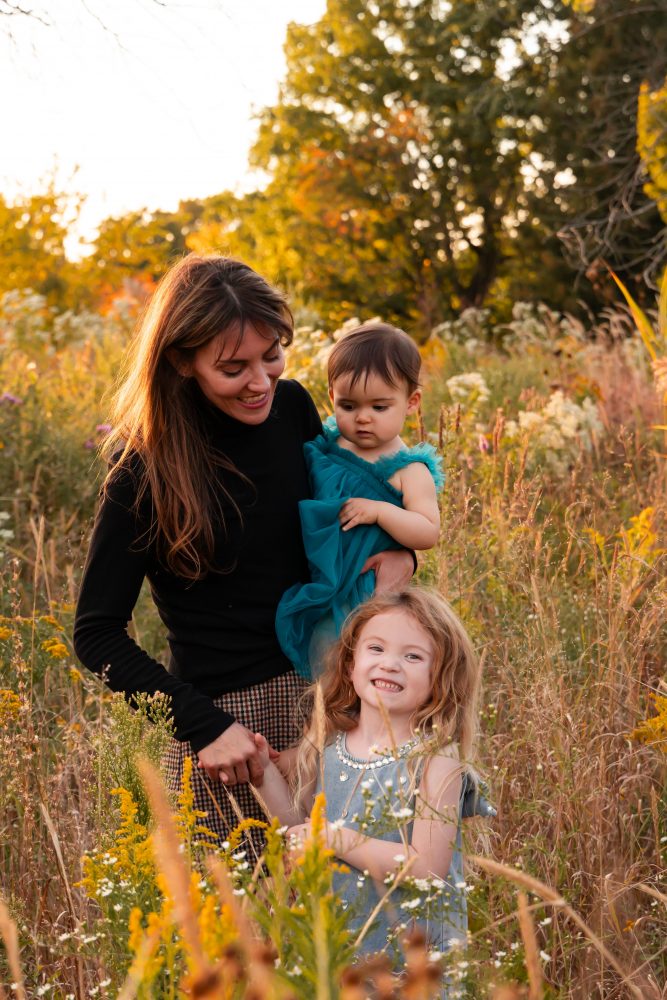 Mother with two young daughters hugging during outdoor sunset photography session in Cleveland Ohio