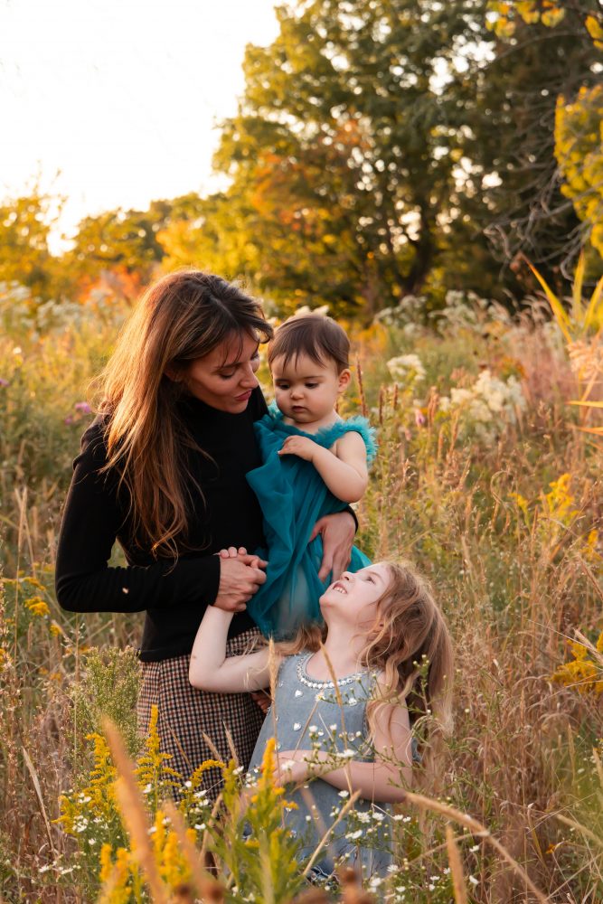 Mother with two young daughters hugging during outdoor sunset photography session in Cleveland Ohio