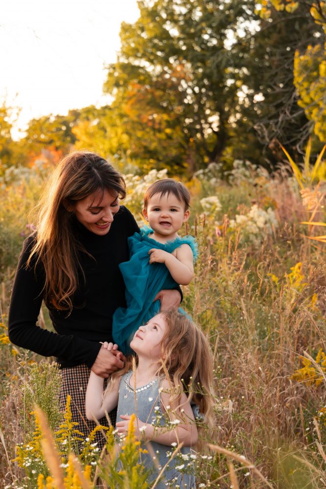 Mother with two young daughters hugging during outdoor sunset photography session in Cleveland Ohio