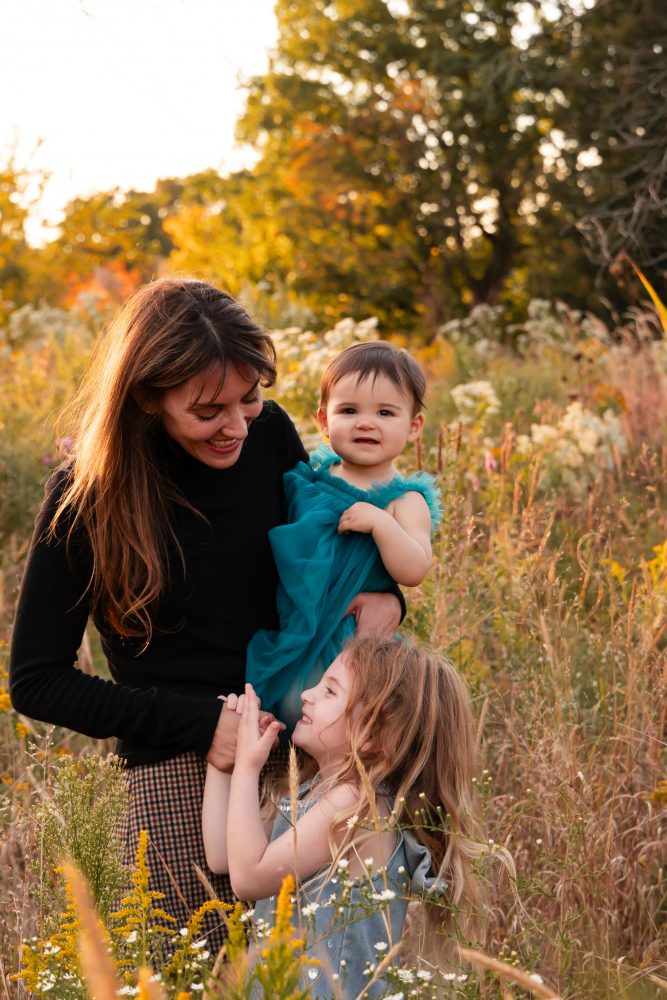 Mother with two young daughters hugging during outdoor sunset photography session in Cleveland Ohio