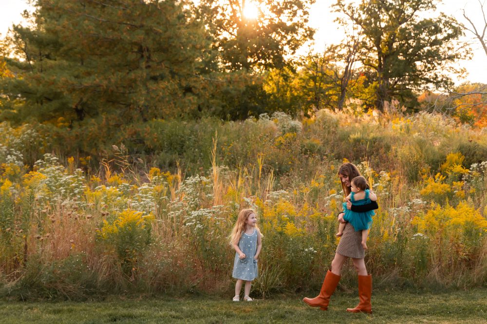 Mother with two young daughters hugging during outdoor sunset photography session in Cleveland Ohio
