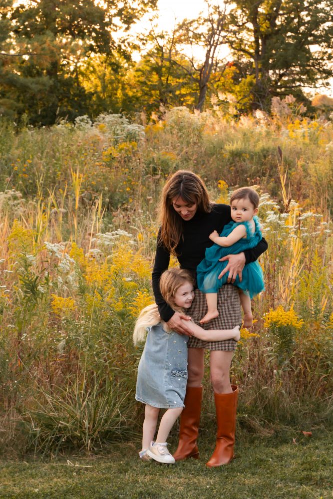 Mother with two young daughters hugging during outdoor sunset photography session in Cleveland Ohio