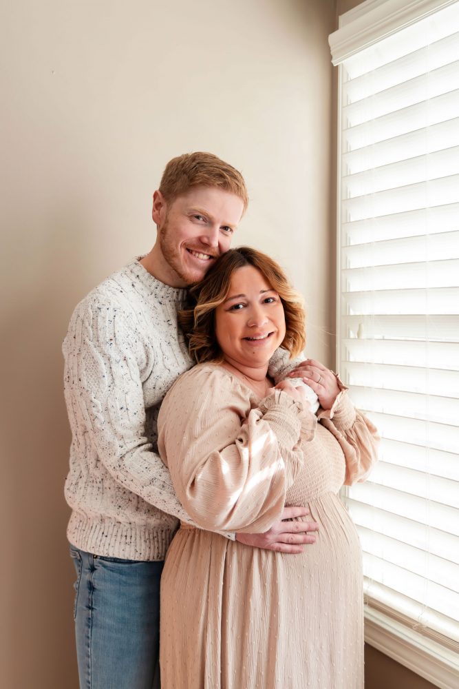 Cleveland maternity photography session of a pregnant mother with her young daughter, captured in soft natural window light by Allison Liffman Photography, highlighting a growing family and sibling connection in a warm, neutral-toned indoor setting