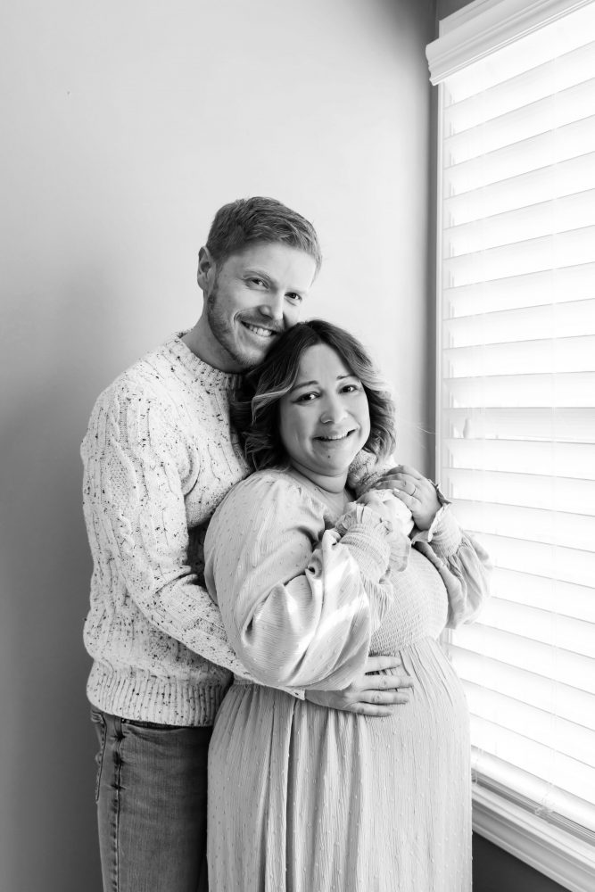 Cleveland maternity photography session of a pregnant mother with her young daughter, captured in soft natural window light by Allison Liffman Photography, highlighting a growing family and sibling connection in a warm, neutral-toned indoor setting