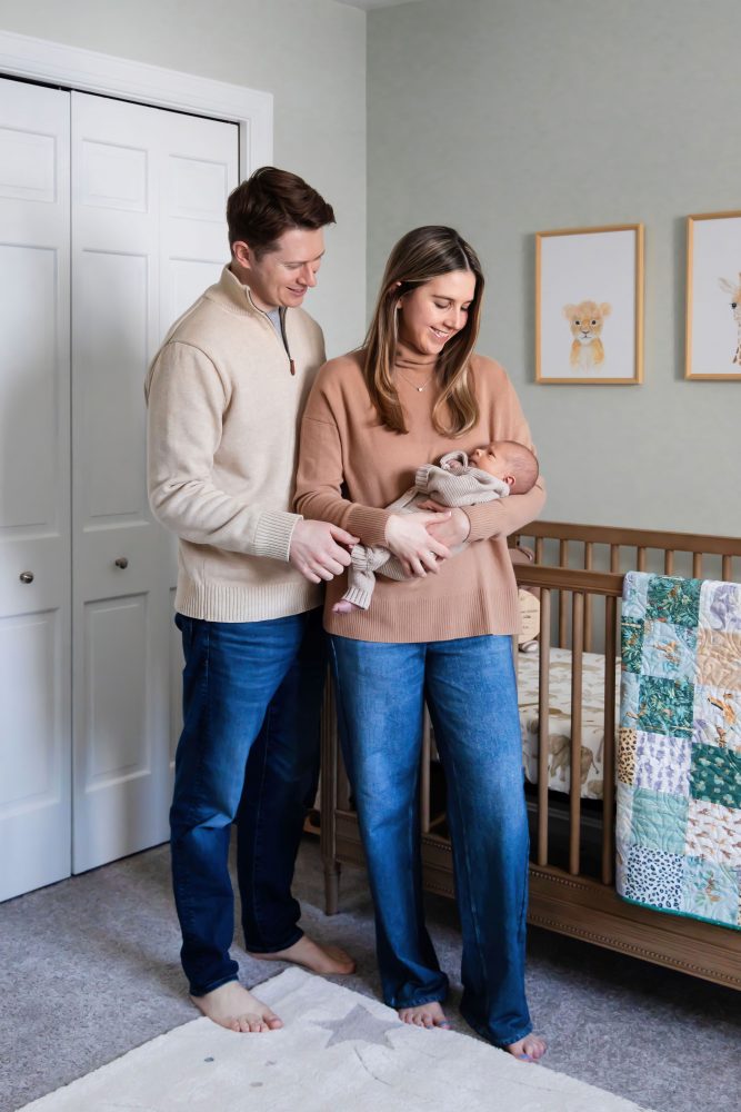 Cleveland newborn and family photographer captures a couple with their newborn baby in a cozy, softly lit nursery, featuring natural light and lifestyle moments in a Cleveland, Ohio home.