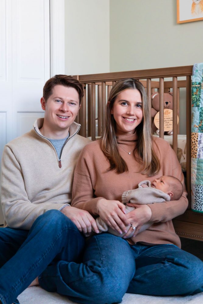Cleveland newborn and family photographer captures a couple with their newborn baby in a cozy, softly lit nursery, featuring natural light and lifestyle moments in a Cleveland, Ohio home.