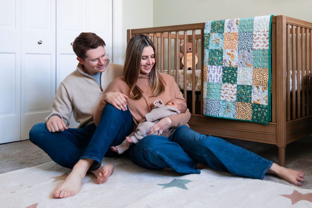 Cleveland newborn and family photographer captures a couple with their newborn baby in a cozy, softly lit nursery, featuring natural light and lifestyle moments in a Cleveland, Ohio home.