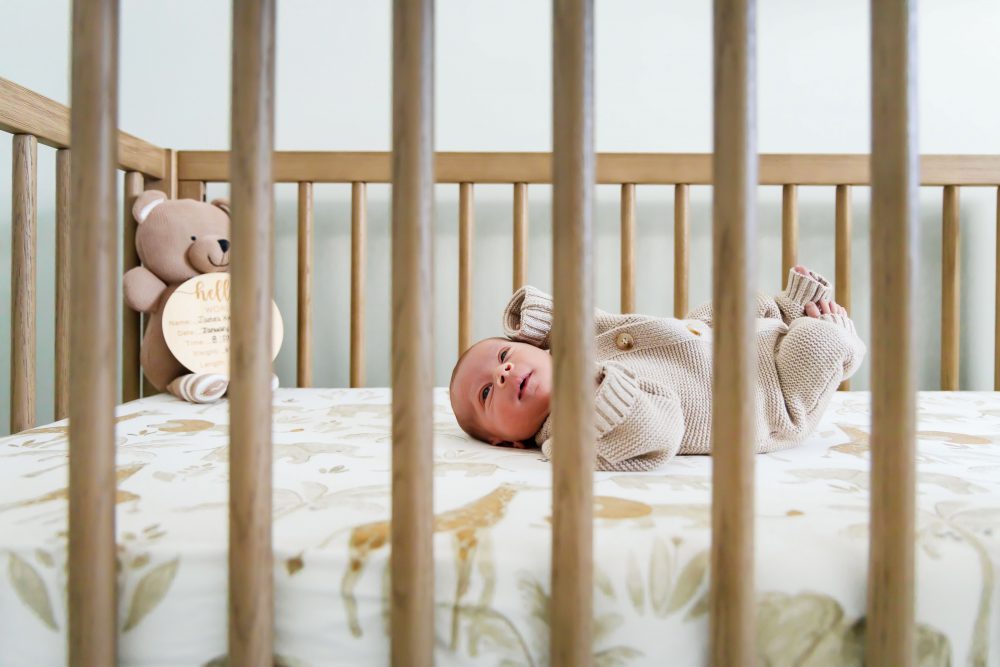 Cleveland newborn and family photographer captures a couple with their newborn baby in a cozy, softly lit nursery, featuring natural light and lifestyle moments in a Cleveland, Ohio home.