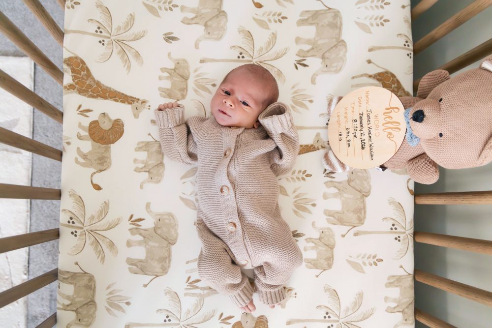 Cleveland newborn and family photographer captures a couple with their newborn baby in a cozy, softly lit nursery, featuring natural light and lifestyle moments in a Cleveland, Ohio home.
