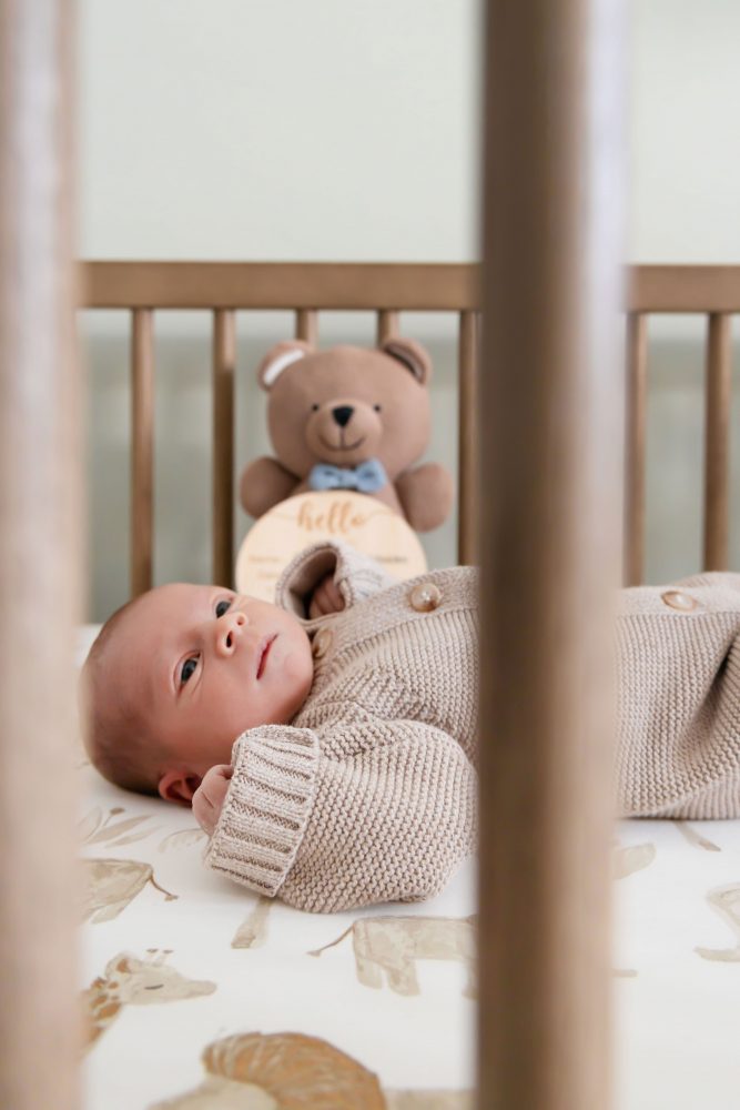 Cleveland newborn and family photographer captures a couple with their newborn baby in a cozy, softly lit nursery, featuring natural light and lifestyle moments in a Cleveland, Ohio home.
