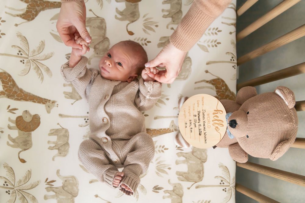 Cleveland newborn and family photographer captures a couple with their newborn baby in a cozy, softly lit nursery, featuring natural light and lifestyle moments in a Cleveland, Ohio home.