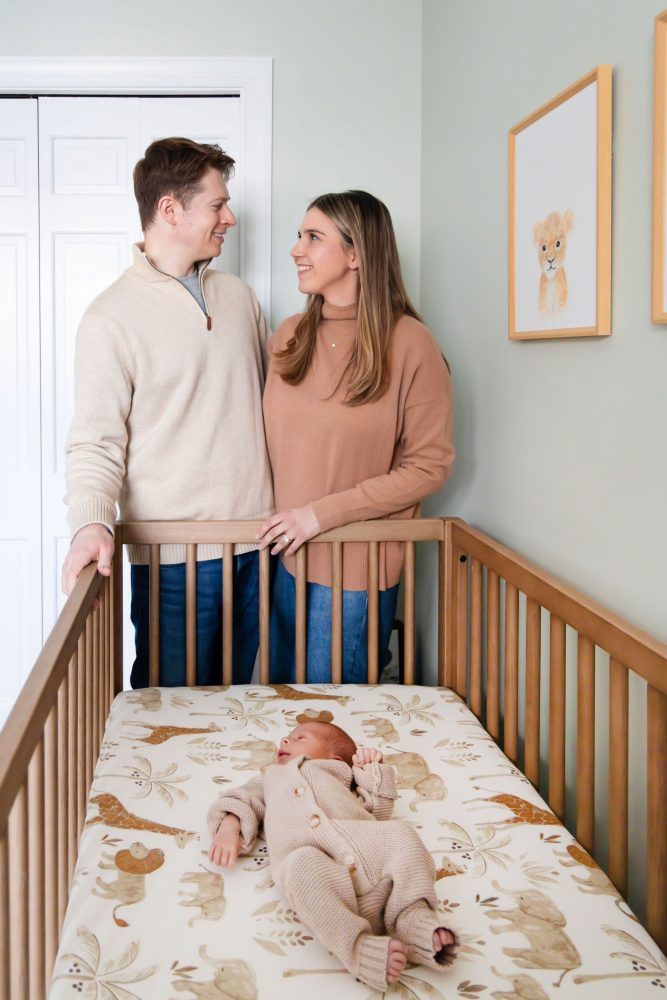 Cleveland newborn and family photographer captures a couple with their newborn baby in a cozy, softly lit nursery, featuring natural light and lifestyle moments in a Cleveland, Ohio home.