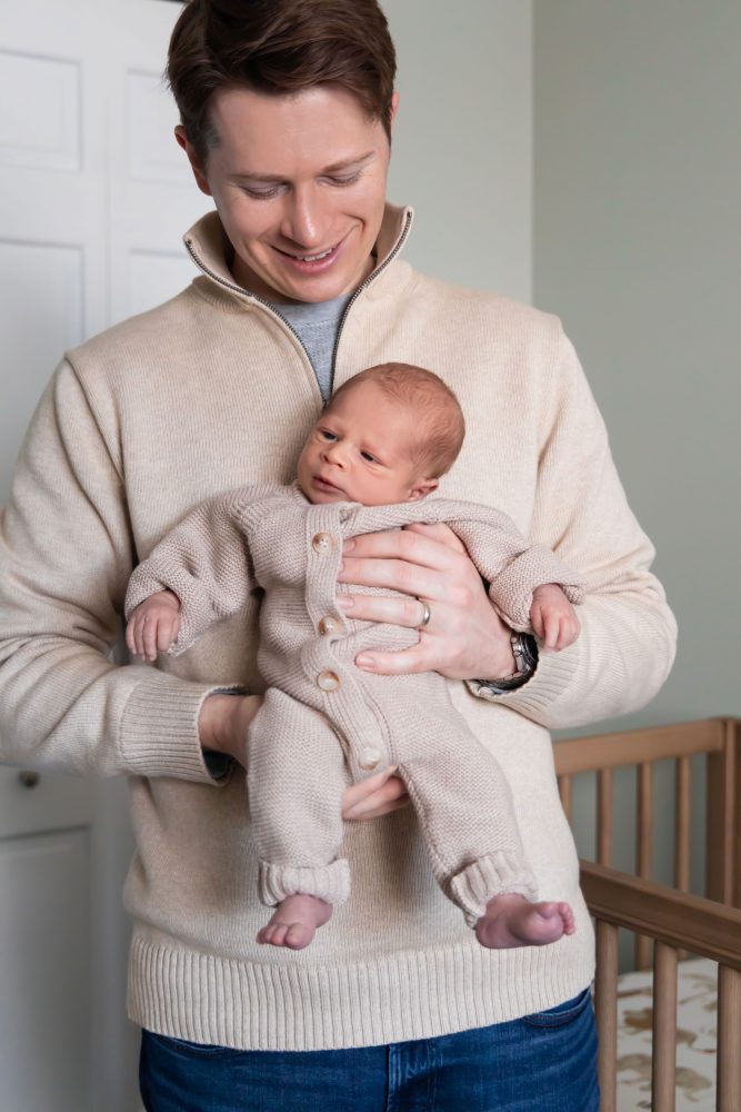 Cleveland newborn and family photographer captures a couple with their newborn baby in a cozy, softly lit nursery, featuring natural light and lifestyle moments in a Cleveland, Ohio home.