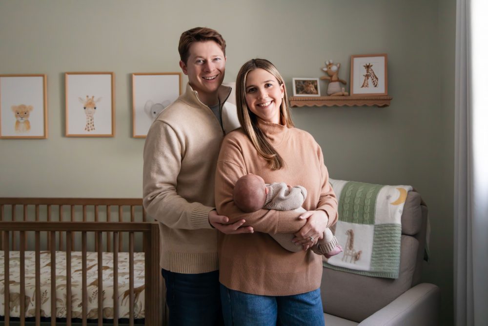 Cleveland newborn and family photographer captures a couple with their newborn baby in a cozy, softly lit nursery, featuring natural light and lifestyle moments in a Cleveland, Ohio home.