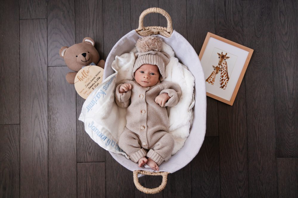 Cleveland newborn and family photographer captures a couple with their newborn baby in a cozy, softly lit nursery, featuring natural light and lifestyle moments in a Cleveland, Ohio home.
