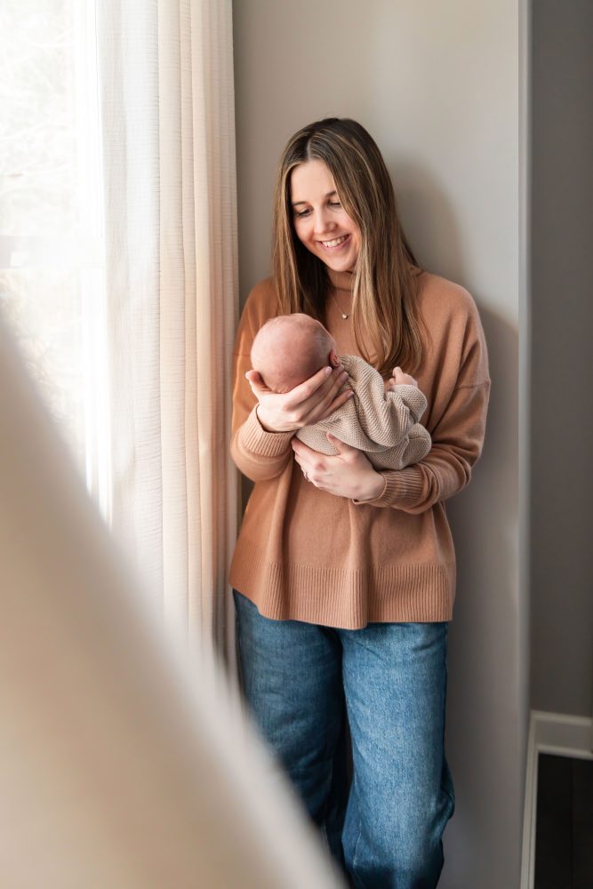Cleveland newborn and family photographer captures a couple with their newborn baby in a cozy, softly lit nursery, featuring natural light and lifestyle moments in a Cleveland, Ohio home.