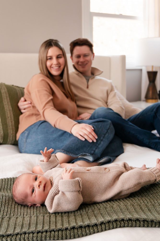 Cleveland newborn and family photographer captures a couple with their newborn baby in a cozy, softly lit nursery, featuring natural light and lifestyle moments in a Cleveland, Ohio home.