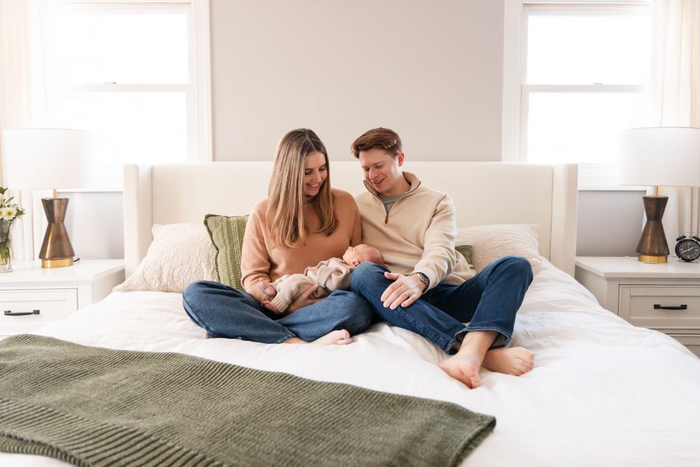 Cleveland newborn and family photographer captures a couple with their newborn baby in a cozy, softly lit nursery, featuring natural light and lifestyle moments in a Cleveland, Ohio home.