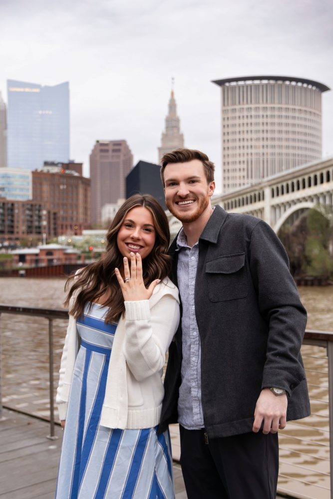 Romantic engagement portrait of newly engaged couple hugging along the Cleveland waterfront skyline