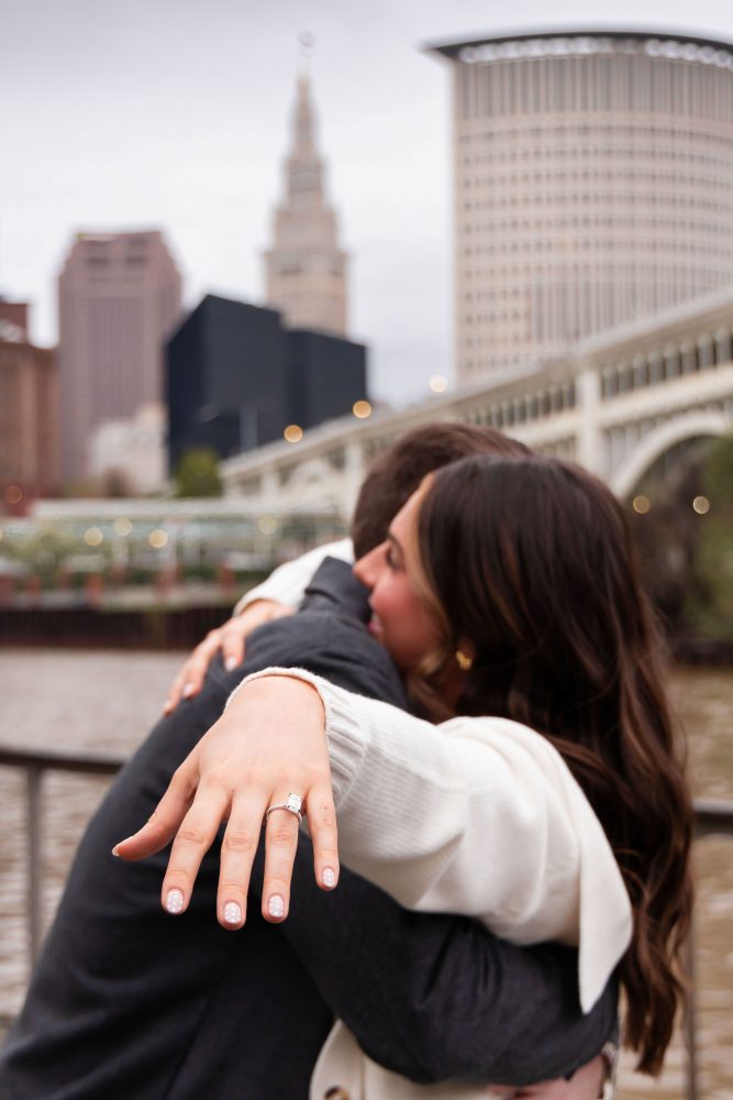 Newly engaged couple showing off engagement ring after surprise proposal in downtown Cleveland