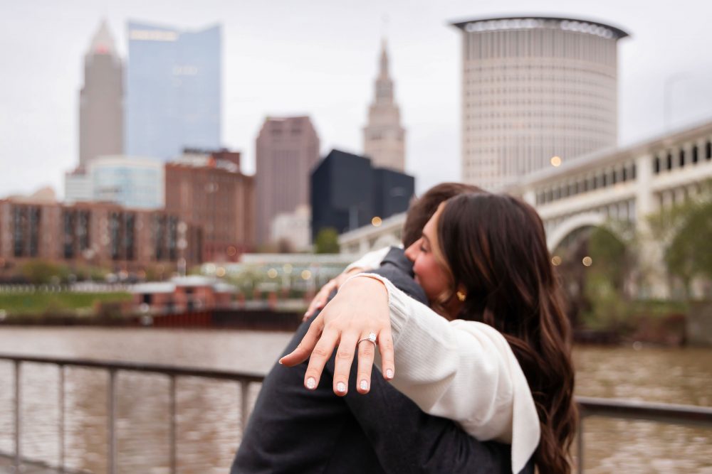 Newly engaged couple showing off engagement ring after surprise proposal in downtown Cleveland